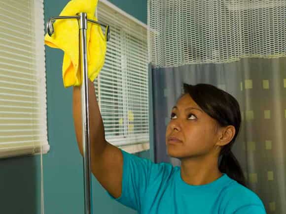 woman cleaning iv pole in hospital